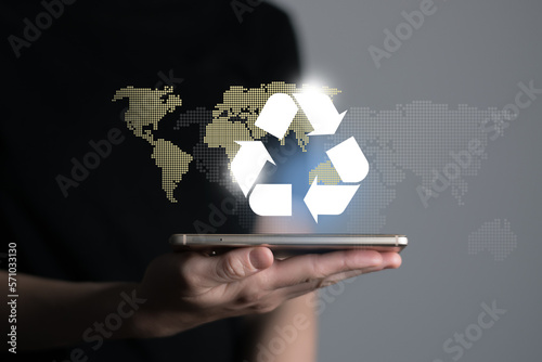 Hand holding recycle symbol on a screen of mobile phone. Mobile applications as asource of information about recycle and sustainability. photo