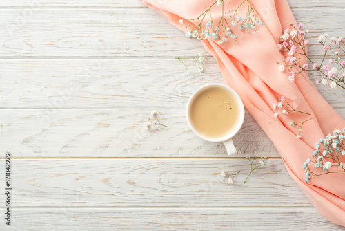 Hello spring concept. Top view photo of cup of frothy coffee gypsophila flowers and pink scarf on grey wooden desk background with blank space