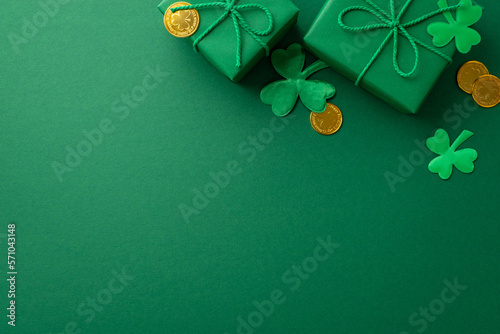 Saint Patrick's Day concept. Top view photo of stylish gift boxes with rope bows gold coins and shamrocks on isolated green background with copyspace