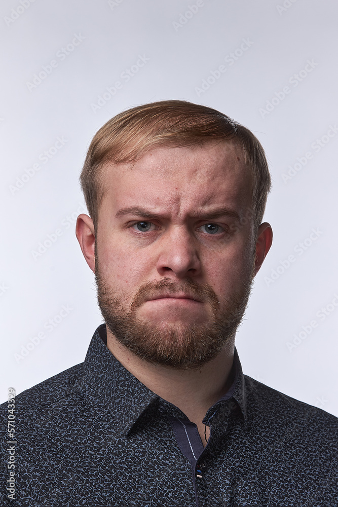 Furious angry young business man, the emotion of resentment of a young man against a light background Furious angry young business man, the emotion of resentment of a young man against a light background