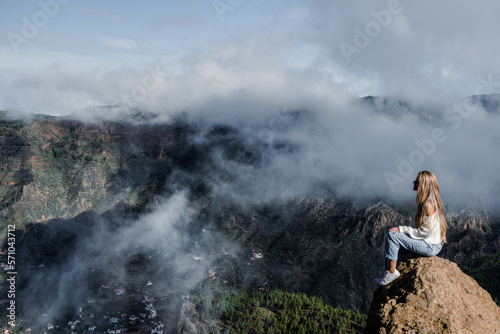 Woman sitting on a rock with the amazing view of Roque Nublo in Gran Canaria