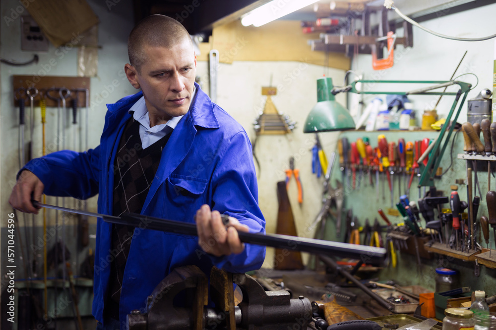 Confident gunsmith lubricates and cleans barrel of a rifled shotgun