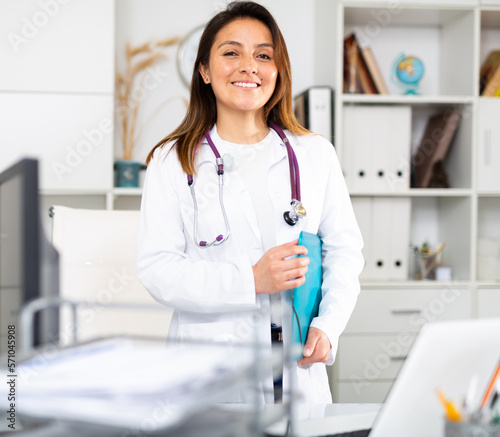 Young female therapist stands with a folder of documents in the office at the clinic