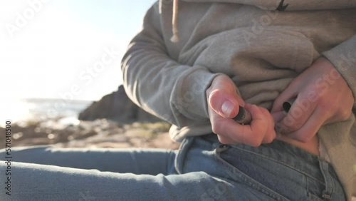 Close-up of woman on a beach giving herself a insulin shot