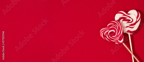 Valentine's Day sweet background. Candy in form of heart on wooden stick on red background. Valentines day concept. Flat lay, top view, copy space