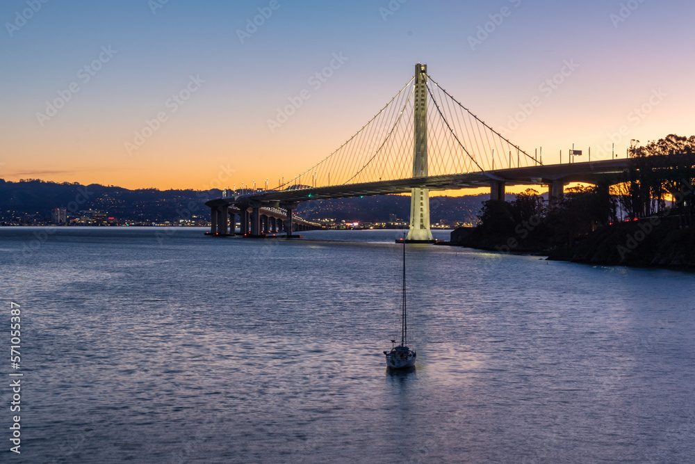 Early morning view of the Bay Bridge with a sailboat in the foreground Early morning view of the Bay Bridge with a sailboat in the foreground