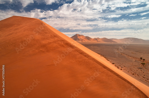 Aerial view of the vast orange dune of the Namib Desert against a blue sky with white clouds.  Namib-Naukluft National Park  Namibia.