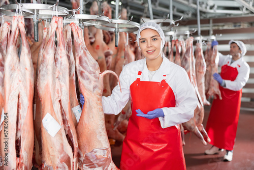 Female butcher showing muttton carcass in meat storage