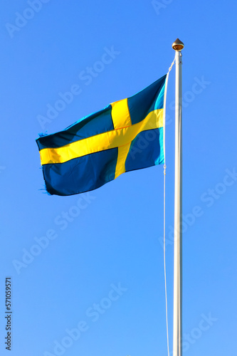 Flag pole with the Swedish national flag with blue sky in the background