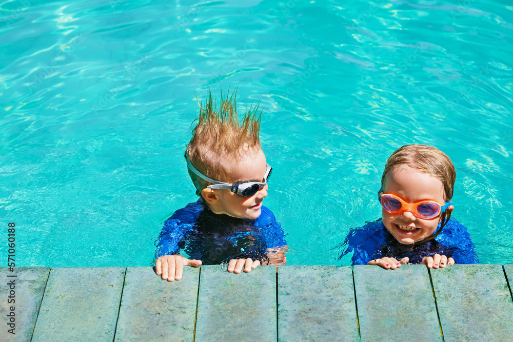 Happy children in wetsuits and goggles learn to swim, have fun at