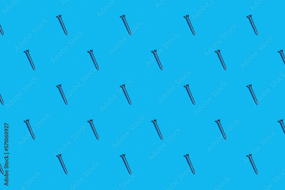 Rows of silver metal screws against a blue background Rows of silver metal screws against a blue background