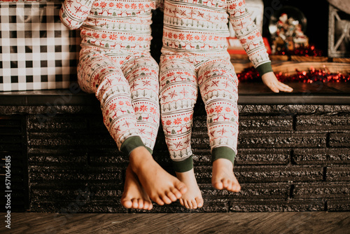 siblings sitting side by side wearing christmas pajamas