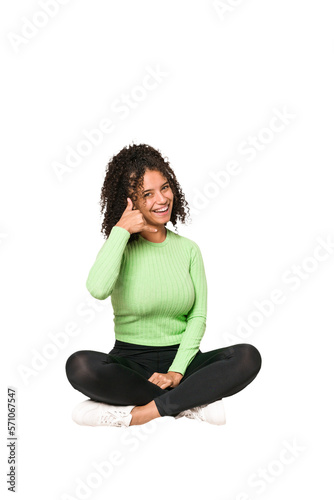 Young african american curly woman sitting on the floor isolated © Asier