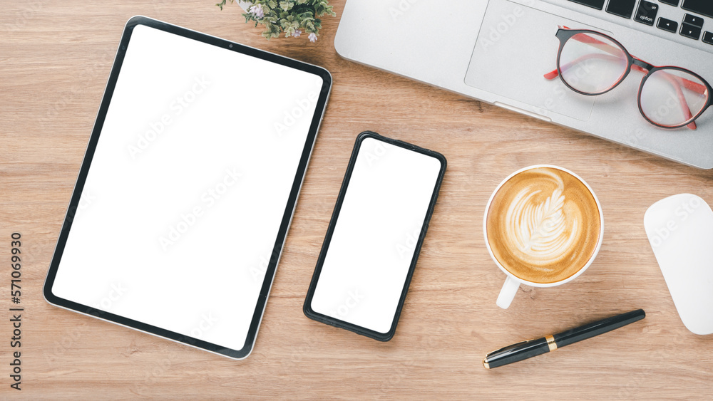 Wooden desk workplace with blank screen digital tablet and smartphone, laptop, eyeglass, mouse, pen and cup of coffee, Top view flat lay. Wooden desk workplace with blank screen digital tablet and smartphone, laptop, eyeglass, mouse, pen and cup of coffee, Top view flat lay.