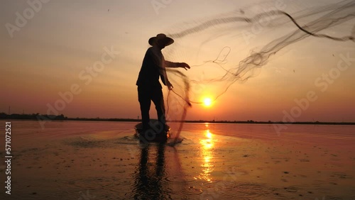 4K Slow Motion, silhouette of fisherman throwing fishing net during sunrise on boats at the lake. Traditional culture of Thailand. Fisherman's life style.