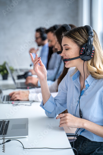 Vertical side view of beautiful blond hair call canter agent working with group of operators in office