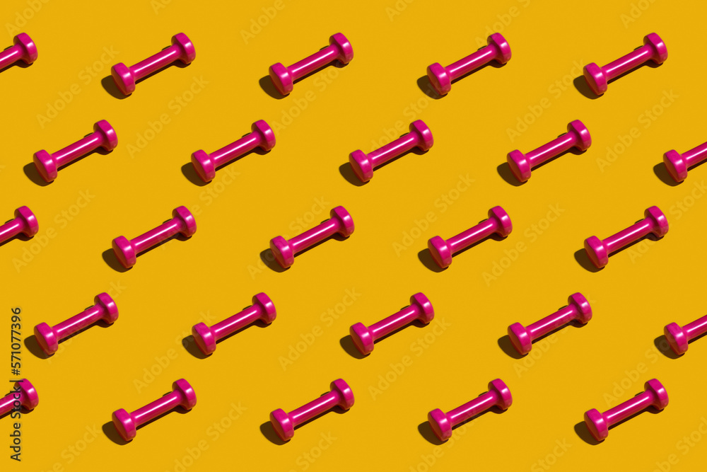 Bright pink dumbbells on a yellow background