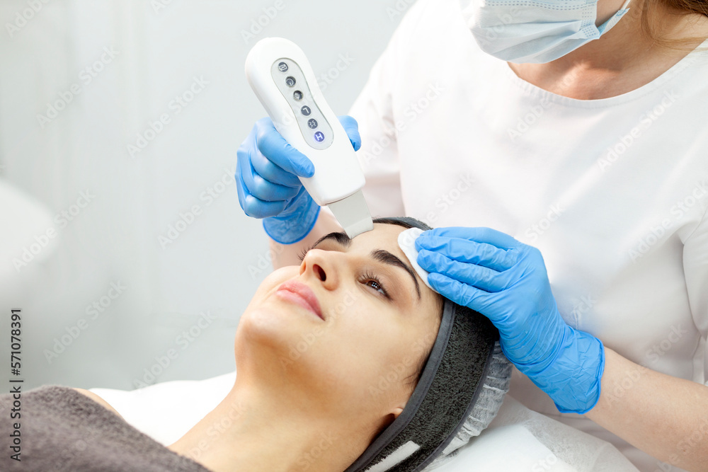 procedure of ultrasonic cavitation facial peeling. facial skin care, woman beautician makes facial cleaning to client