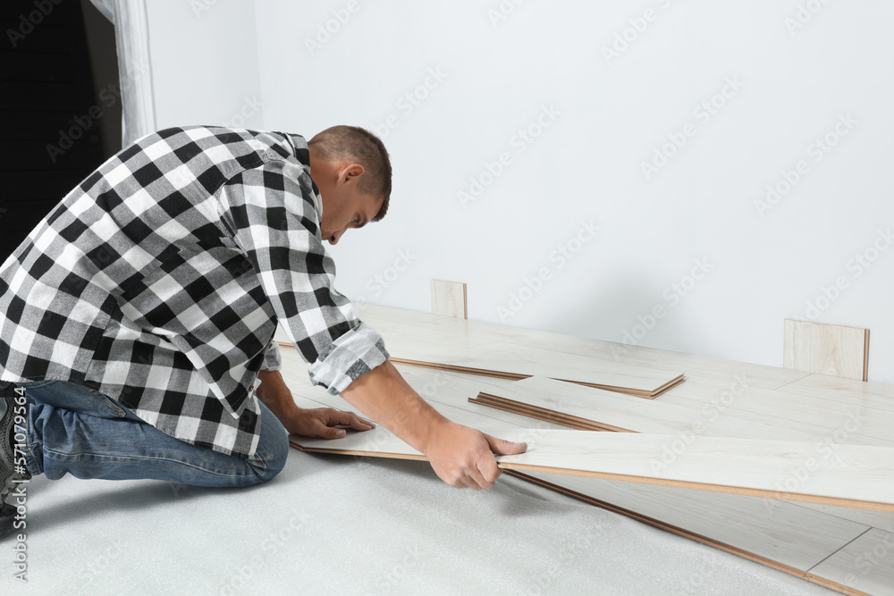Professional worker installing new laminate flooring indoors Professional worker installing new laminate flooring indoors