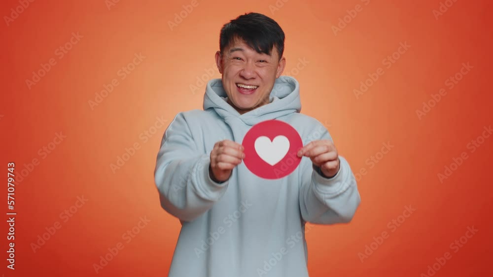 Like. Happy lovely asian man show heart banner inscription agrees with something, gives positive reply recommends advertisement likes good. Excited handsome guy isolated on orange studio background Like. Happy lovely asian man show heart banner inscription agrees with something, gives positive reply recommends advertisement likes good. Excited handsome guy isolated on orange studio background
