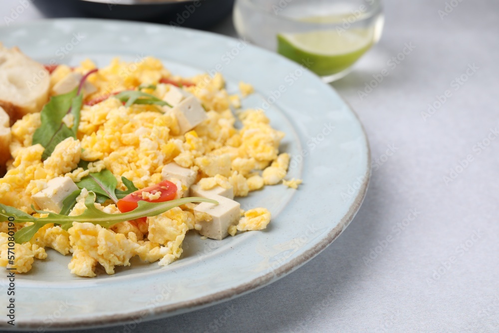 Plate with delicious scrambled eggs and tofu on white table, closeup