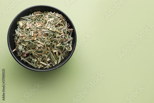 Bowl with aromatic dried lemongrass on light green background, top view. Space for text