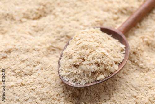 Wooden spoon of brewer`s yeast on flakes, closeup. Space for text photo