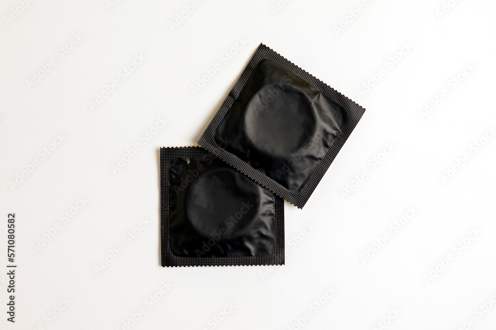 Fototapeta premium black condom on white background, top view, safe sex concept