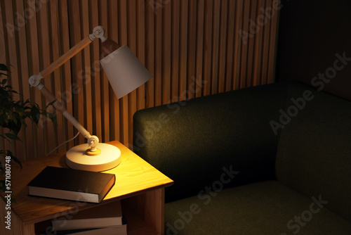 Stylish modern desk lamp and book on wooden cabinet in living room