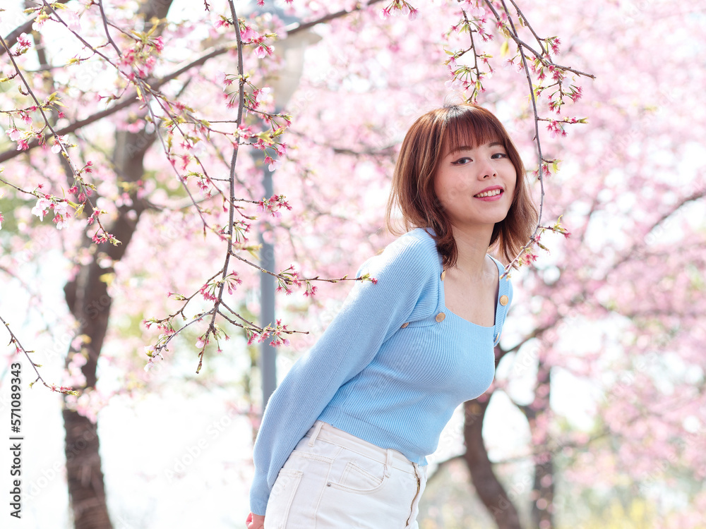 Outdoor portrait of beautiful young Chinese girl posing with blossom cherry tree brunch background in spring garden, beauty, summer, emotion, lifestyle, expression and people concept. Outdoor portrait of beautiful young Chinese girl posing with blossom cherry tree brunch background in spring garden, beauty, summer, emotion, lifestyle, expression and people concept.