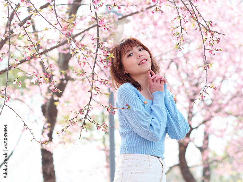 Outdoor portrait of beautiful young Chinese girl posing with blossom cherry tree brunch background in spring garden, beauty, summer, emotion, lifestyle, expression and people concept. Outdoor portrait of beautiful young Chinese girl posing with blossom cherry tree brunch background in spring garden, beauty, summer, emotion, lifestyle, expression and people concept.