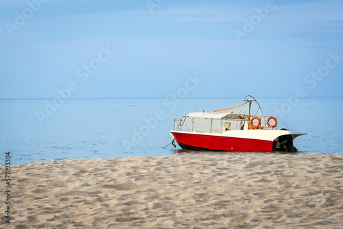 Red and white color speed boat on the beach, copy space. © sinseeho