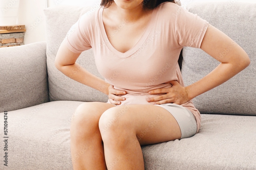 Young woman using her hands touching and squeezing her tummy Feeling painful after eating something unhygienic or during her menstrual period Women health and medical treatment concept Young woman using her hands touching and squeezing her tummy Feeling painful after eating something unhygienic or during her menstrual period Women health and medical treatment concept