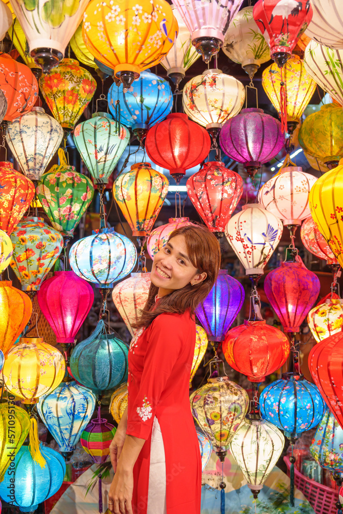 happy woman wearing Ao Dai Vietnamese dress with colorful lanterns, traveler sightseeing at Hoi An ancient town in central Vietnam.landmark for tourist attractions.Vietnam and Southeast travel concept