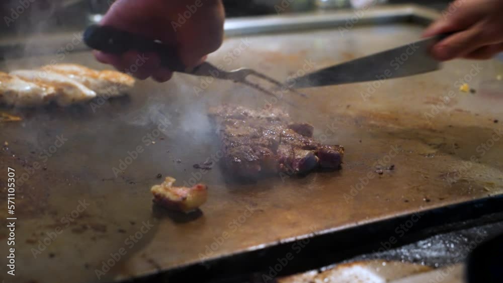 Chef cubes steak as it sears on hibachi grill, slow motion close up 4K Chef cubes steak as it sears on hibachi grill, slow motion close up 4K