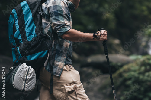 Hikers use trekking pole with backpacks standing on the rock through in the forest. hiking and adventure concept.