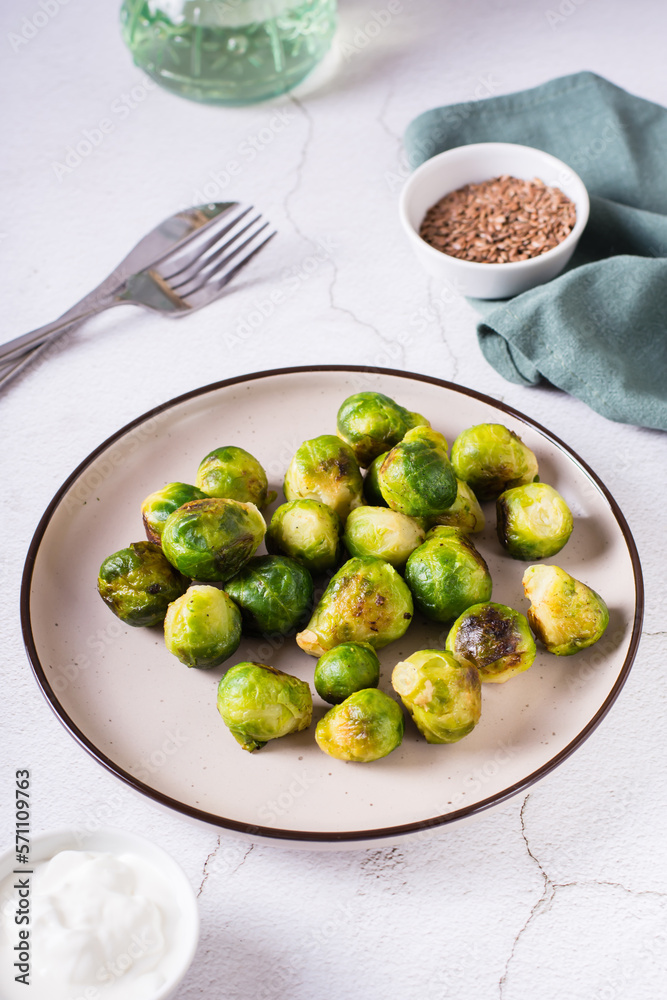 Homemade roasted Brussels sprouts on a plate and sauce in a bowl on the table. Vertical view Homemade roasted Brussels sprouts on a plate and sauce in a bowl on the table. Vertical view