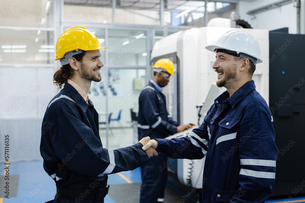male engineers smiling wear helmets safety shake hands partner success at factory workshop. professional technician agreement plan production factory. male engineers smiling wear helmets safety shake hands partner success at factory workshop. professional technician agreement plan production factory.