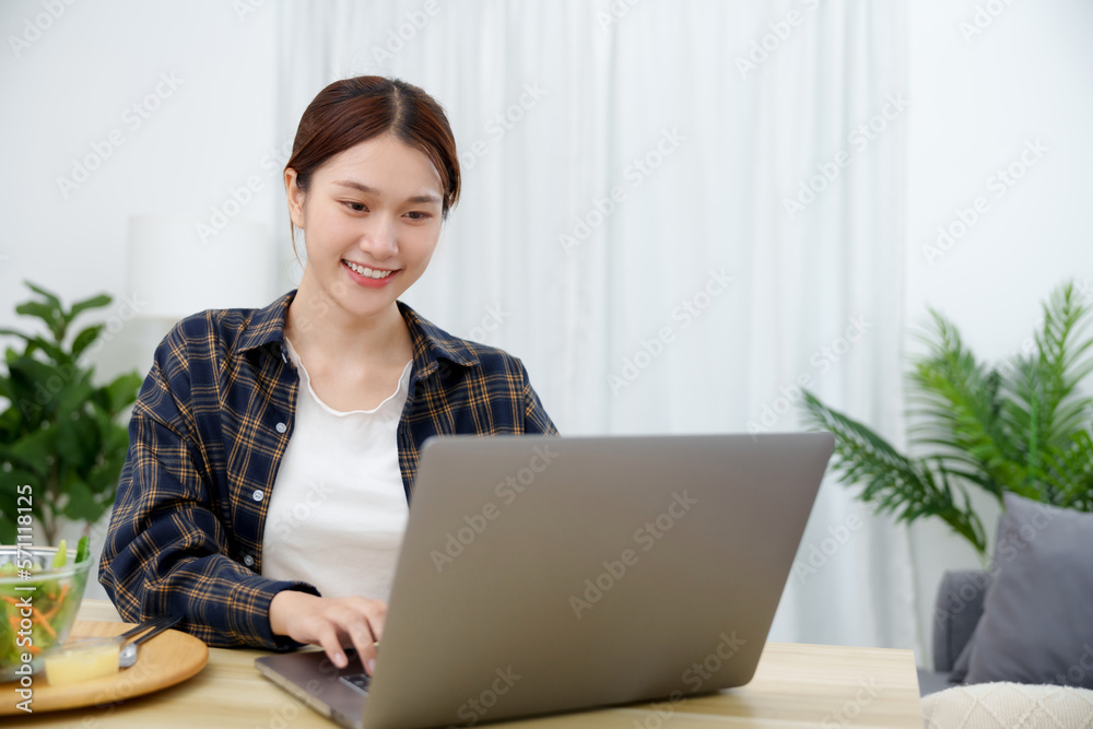 Asian businesswoman having lunch break and typing on the laptop. working at home concept Asian businesswoman having lunch break and typing on the laptop. working at home concept