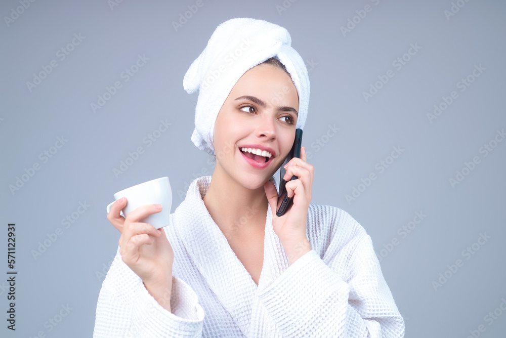 Morning coffee. Portrait of smiling woman with cup of coffee talking on phone above morning news. Smiling girl talking on phone drinking coffee isolated on gray studio background. Morning phone talk. Morning coffee. Portrait of smiling woman with cup of coffee talking on phone above morning news. Smiling girl talking on phone drinking coffee isolated on gray studio background. Morning phone talk.