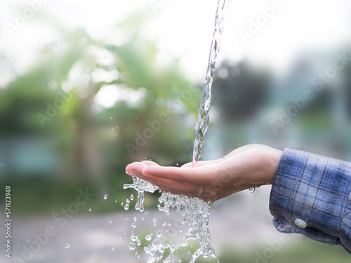 Pouring Water on Hand Farmer with blur Growth Green Plant Tree Background,Fresh Liquid Pur Water Falling Hygiene Clean on Palm up Woman,Ecology,Environment,save the world,conservation Global,Eart Day.