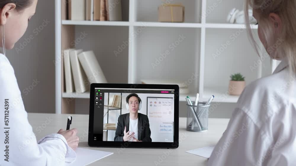 Video presentation. Business webinar. Remote conference. Confident male coach in headphones reporting statistics analysis to female colleagues on tablet at digital office. Video presentation. Business webinar. Remote conference. Confident male coach in headphones reporting statistics analysis to female colleagues on tablet at digital office.