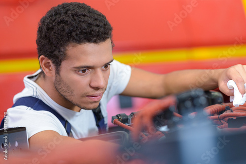 young man trying to repair a car engine photo