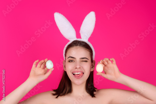 Woman with bunny ears and easter eggs. Easter bunny isolated on studio background. Holidays, spring and party concept. Portrait of lovely, cheerful girl in rabbit ears celebrating Easter.