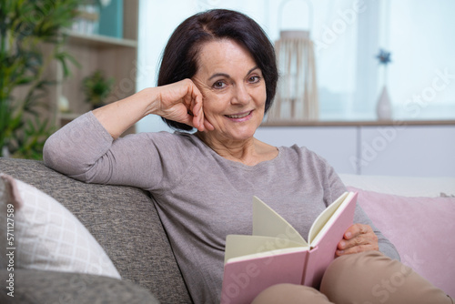 senior woman reading on couch at home