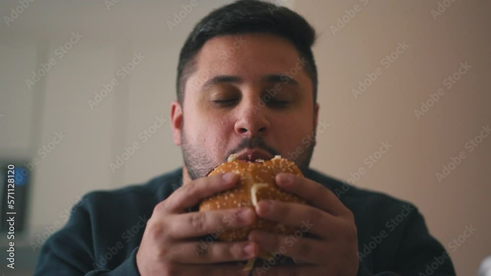 Relieved young man hungry eating a hamburger Relieved young man hungry eating a hamburger
