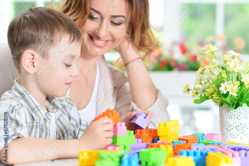 Woman and little boy playing with colorful plastic blocks 