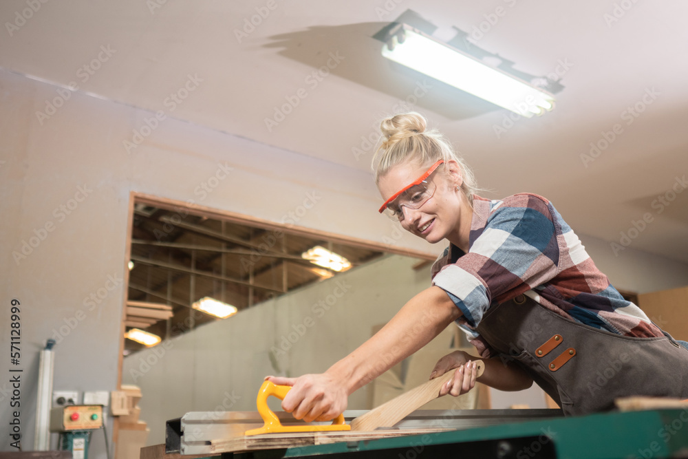 Young carpenter woman wearing glasses and working in wood workshop Young carpenter woman wearing glasses and working in wood workshop