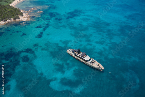 An impressive open yacht near the shore, created specifically for communication and relaxation, view from above. Anchorage of a large yacht on transparent water, top view. © Berg