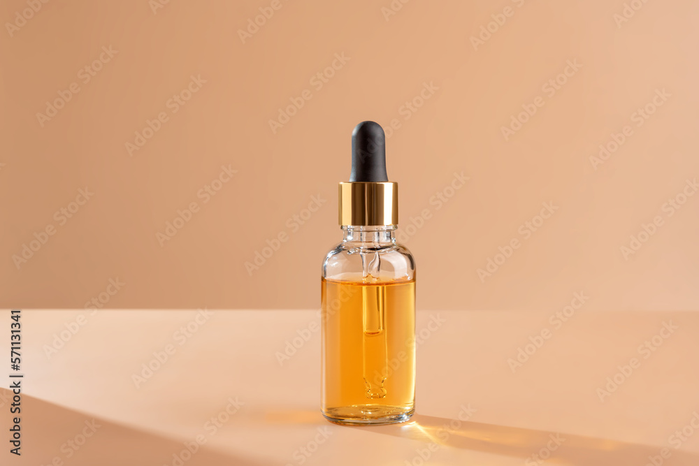 A glass dropper bottle with beauty care serum, hyaluronic acid and vitamins on blue background with trendy hard shadows. Home cosmetics and spa concept A glass dropper bottle with beauty care serum, hyaluronic acid and vitamins on blue background with trendy hard shadows. Home cosmetics and spa concept